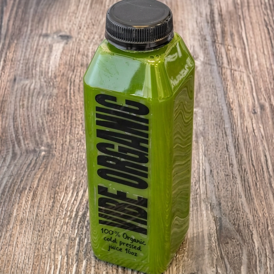Green bottled organic cold-pressed juice labeled Green Machine standing on a rustic wooden table.